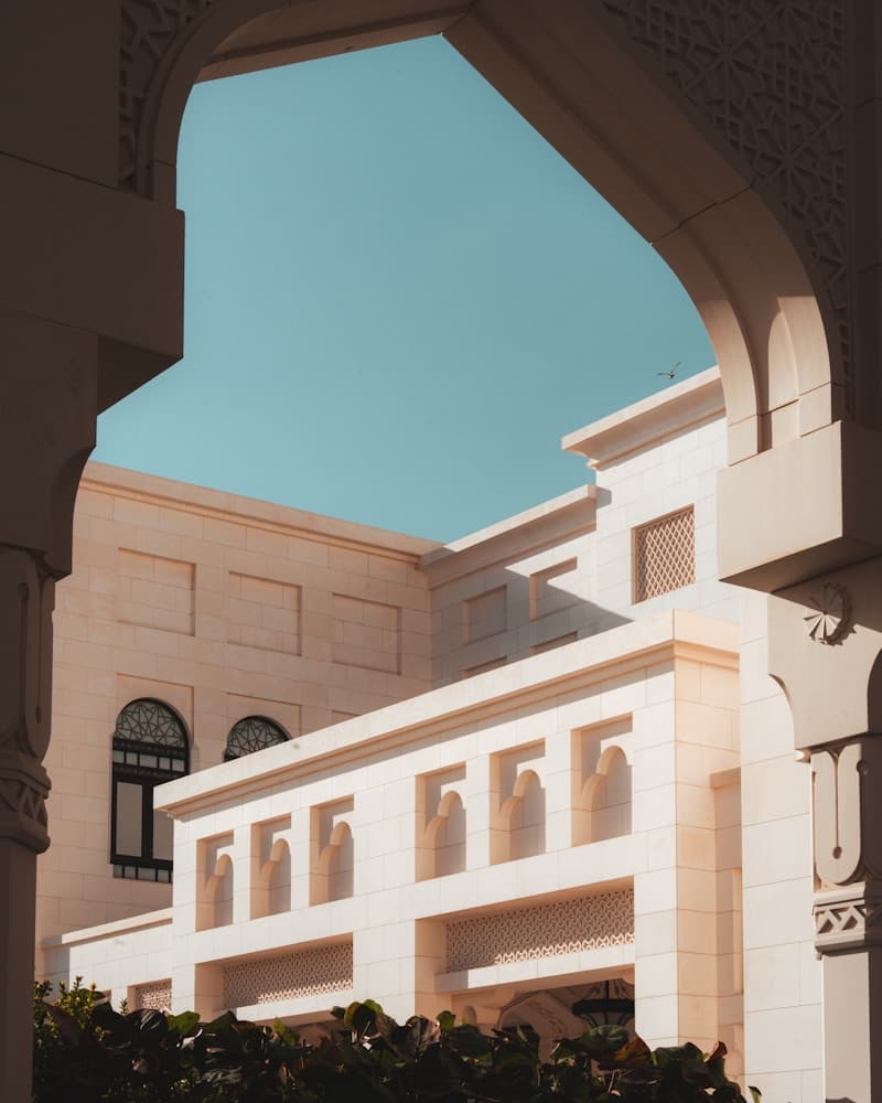Sunlit Moorish architectural courtyard framed by an elegant stone archway