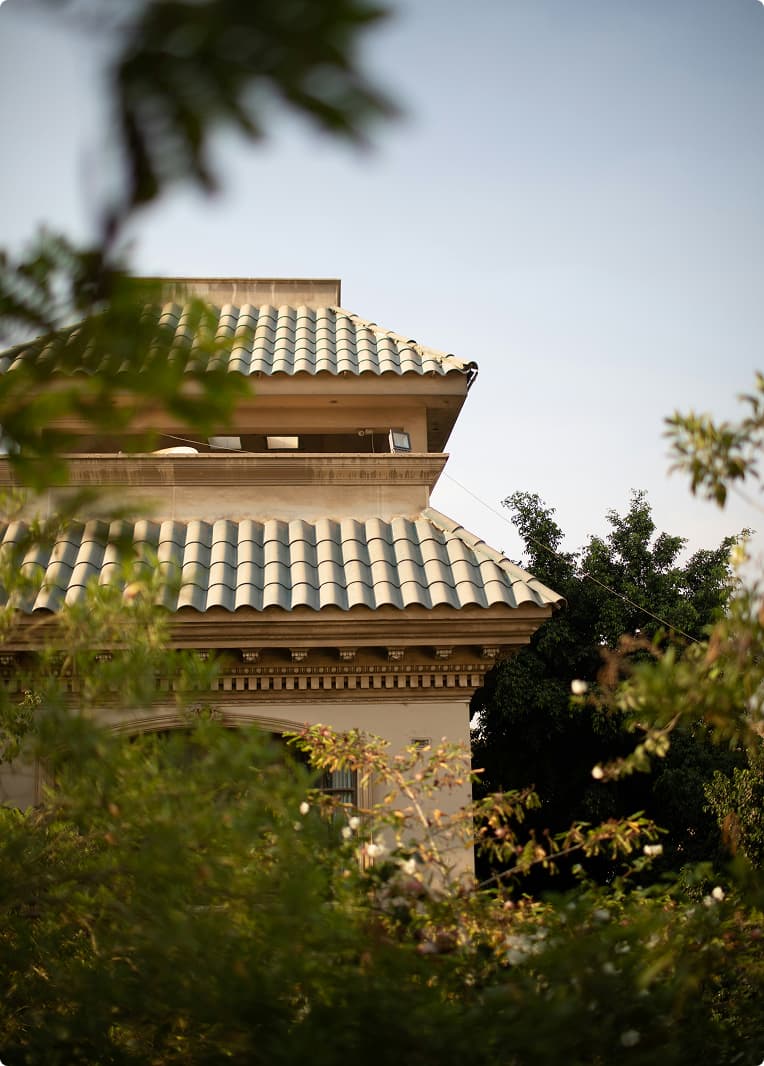 Traditional stone villa with clay-tiled roof surrounded by lush green trees