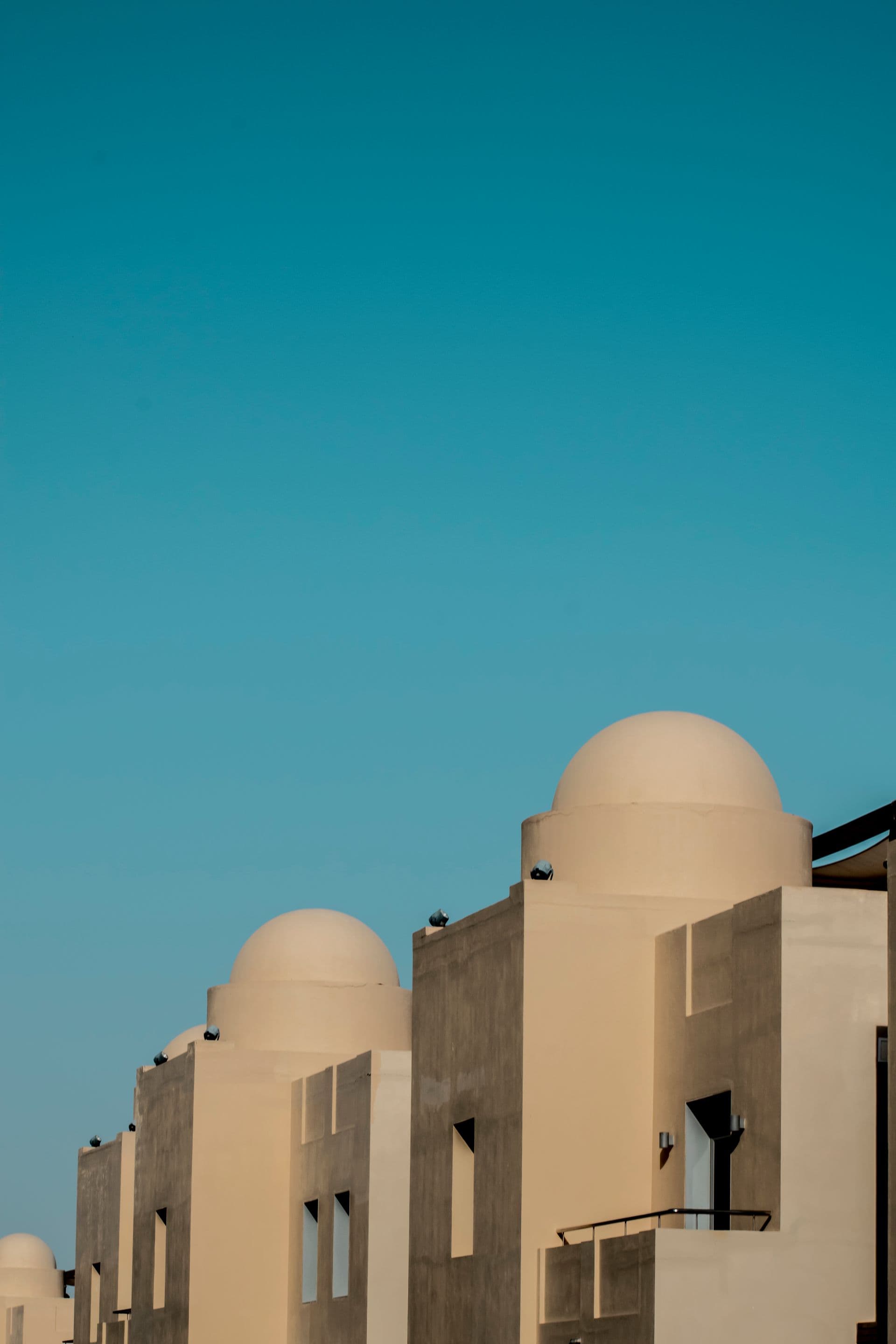 Cubist white and cream buildings with traditional dome rooftops against a vibrant blue sky