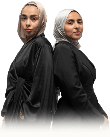Co-founders Samar and Salma standing back-to-back in black abayas and matching hijabs
