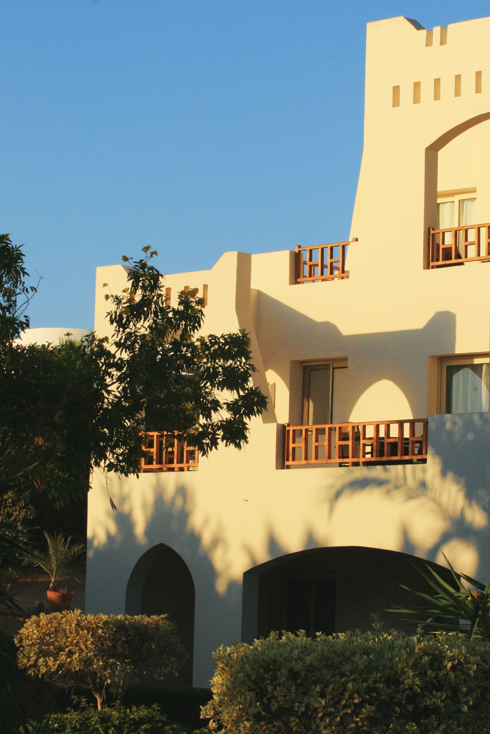 Sunlit adobe-style desert estate with distinctive curved arches and warm earth tones