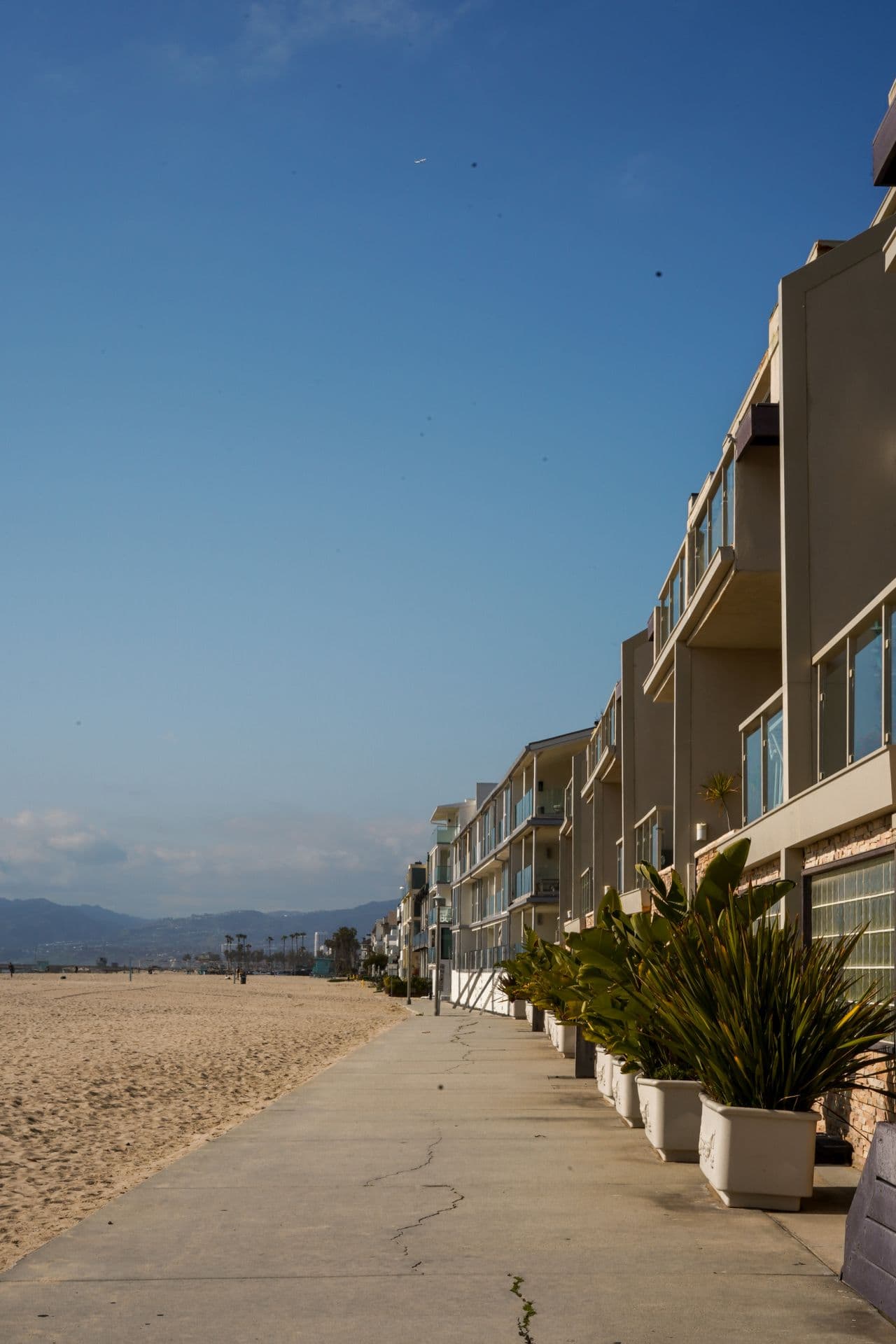 Modern beachfront residential complex with private balconies along a paved coastal promenade
