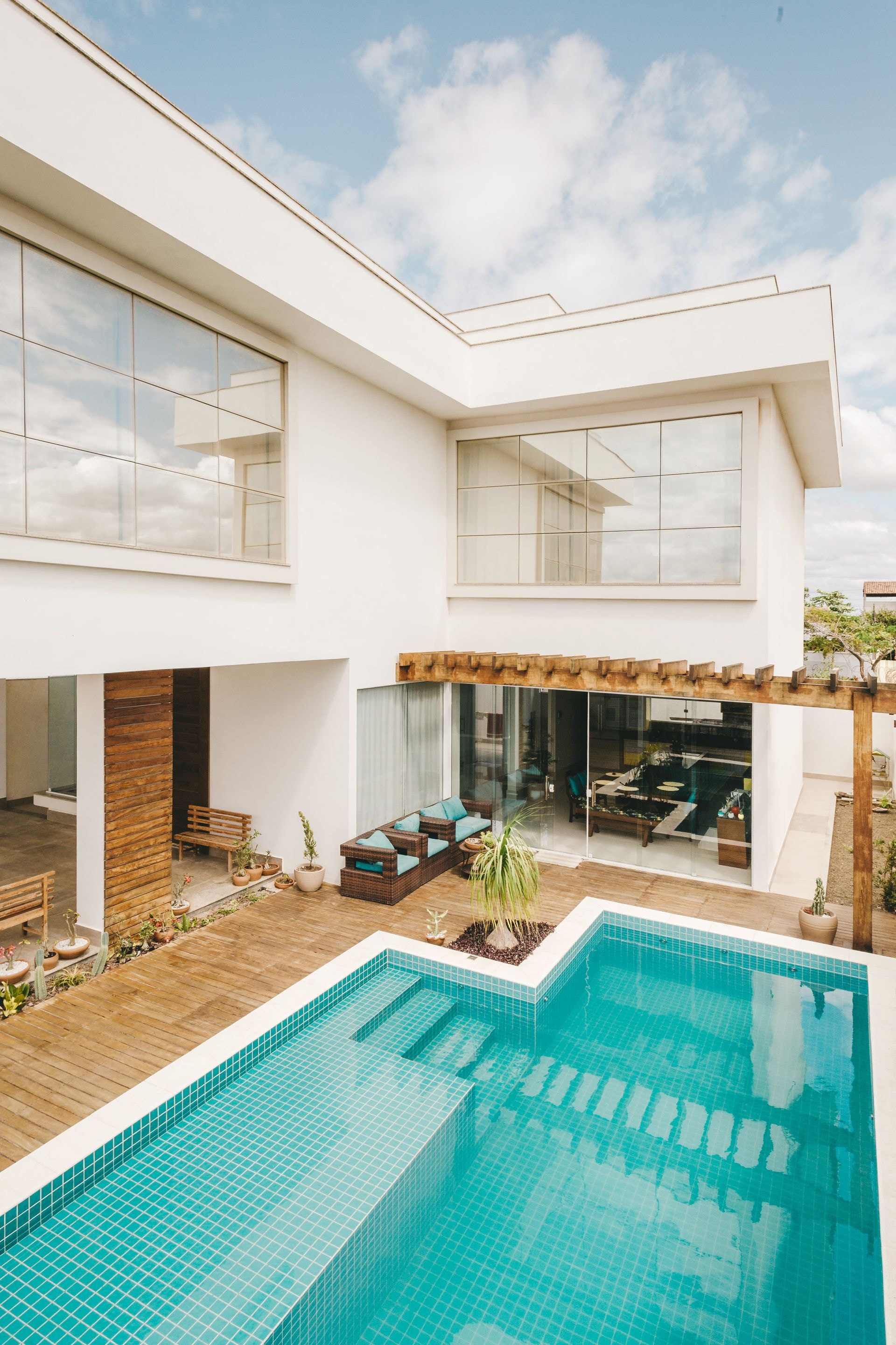 Two-story white modern residence with an outdoor patio lounge beside a private pool