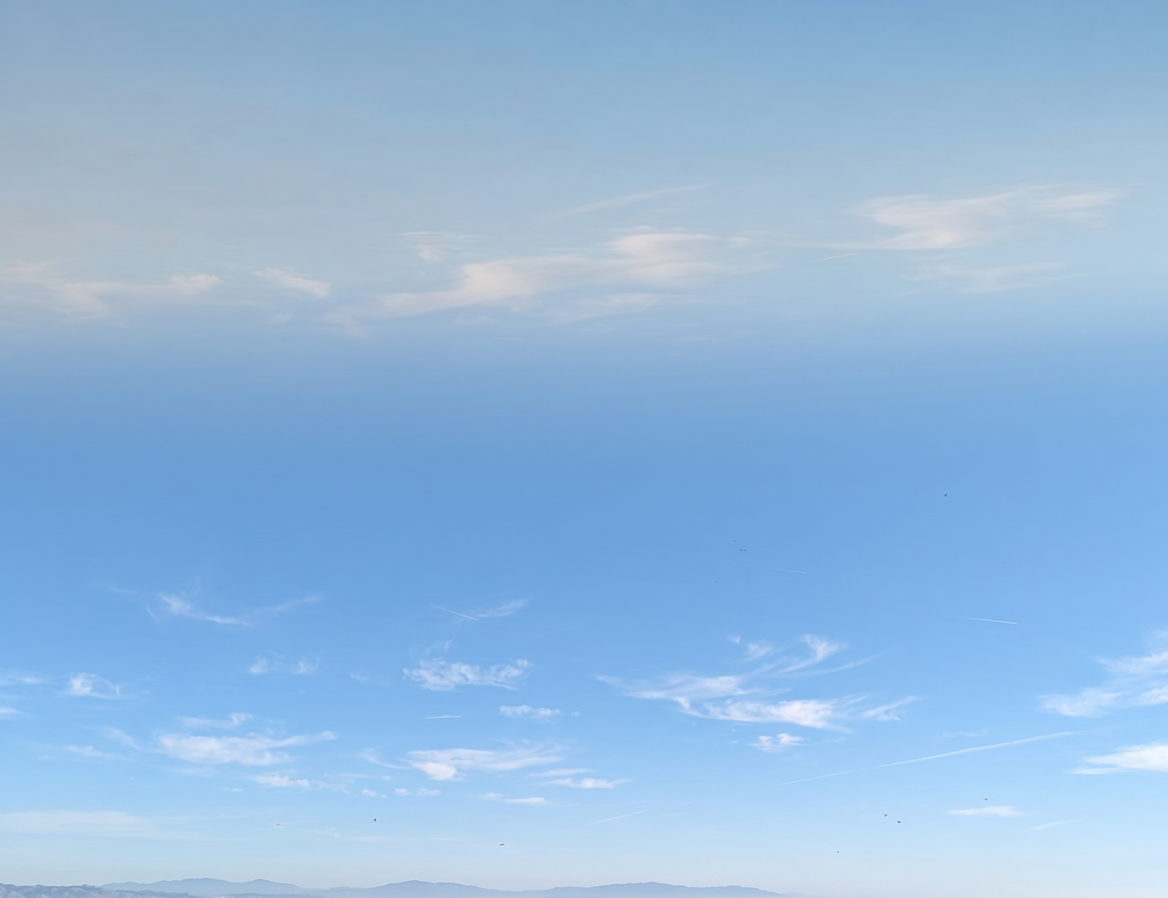 Clear blue sky with soft white clouds
